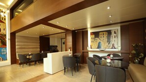 Un moderno vestíbulo de hotel con mostrador de recepción, zona de estar y un cuadro grande en la pared.