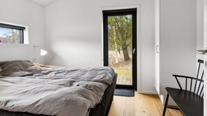 A bedroom with a bed, a desk, and a door leading to an outdoor area.