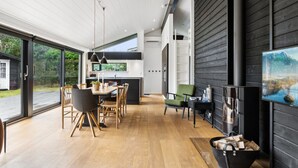 A modern kitchen with a large island, wooden flooring, and a dining area with a table and chairs.