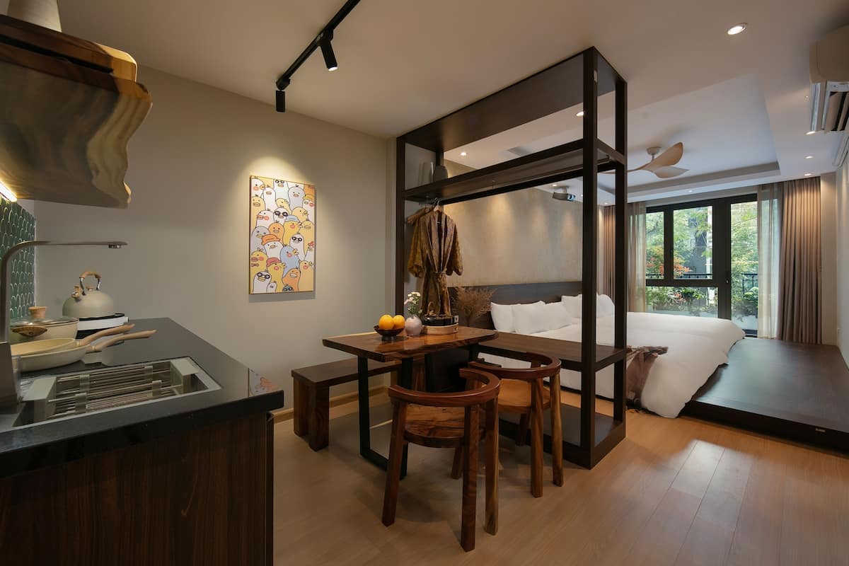Ein modernes Hotelzimmer mit einem Holztisch, Stühlen, einem Bett mit Blick und einem großen Fenster.