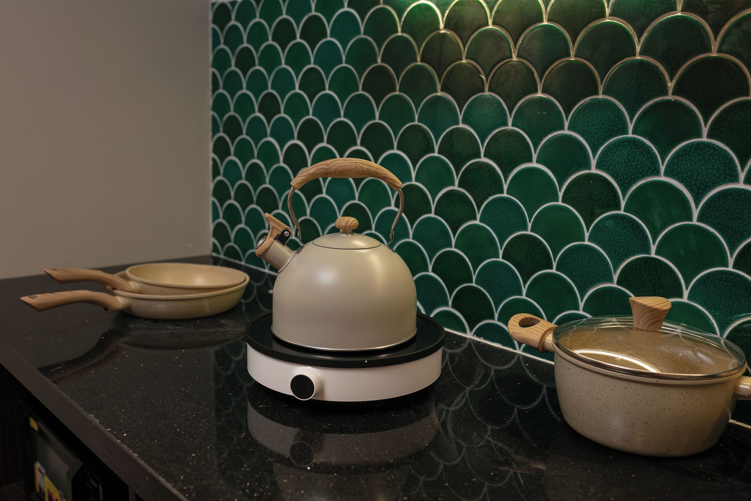 A kitchen counter with a kettle, a frying pan, and a pot.