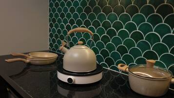 A kitchen counter with a kettle, a frying pan, and a pot.