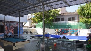 An outdoor pool area with a pool table, benches, and a covered seating area. - Vientiane garden hostel (Vientiane)