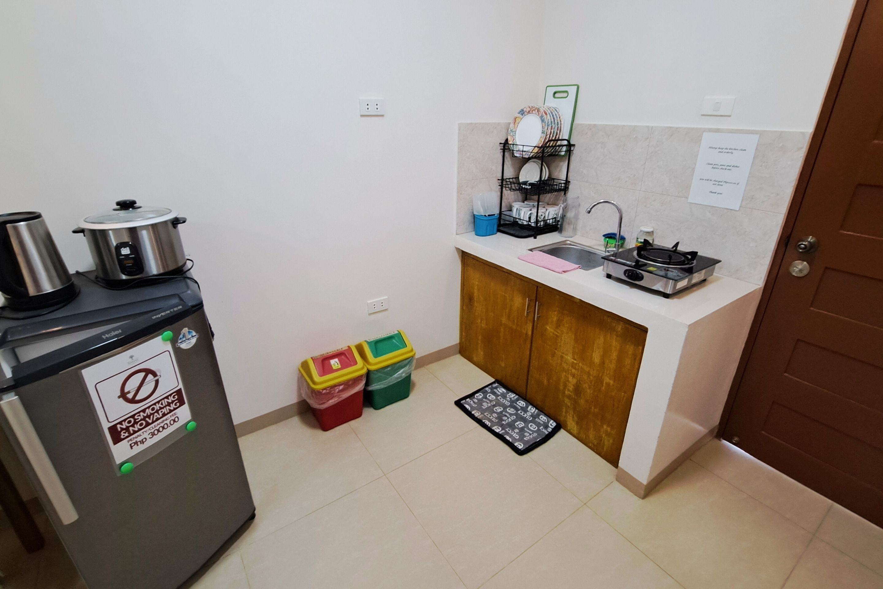A compact kitchen with a refrigerator, stove, sink, and a dish rack.