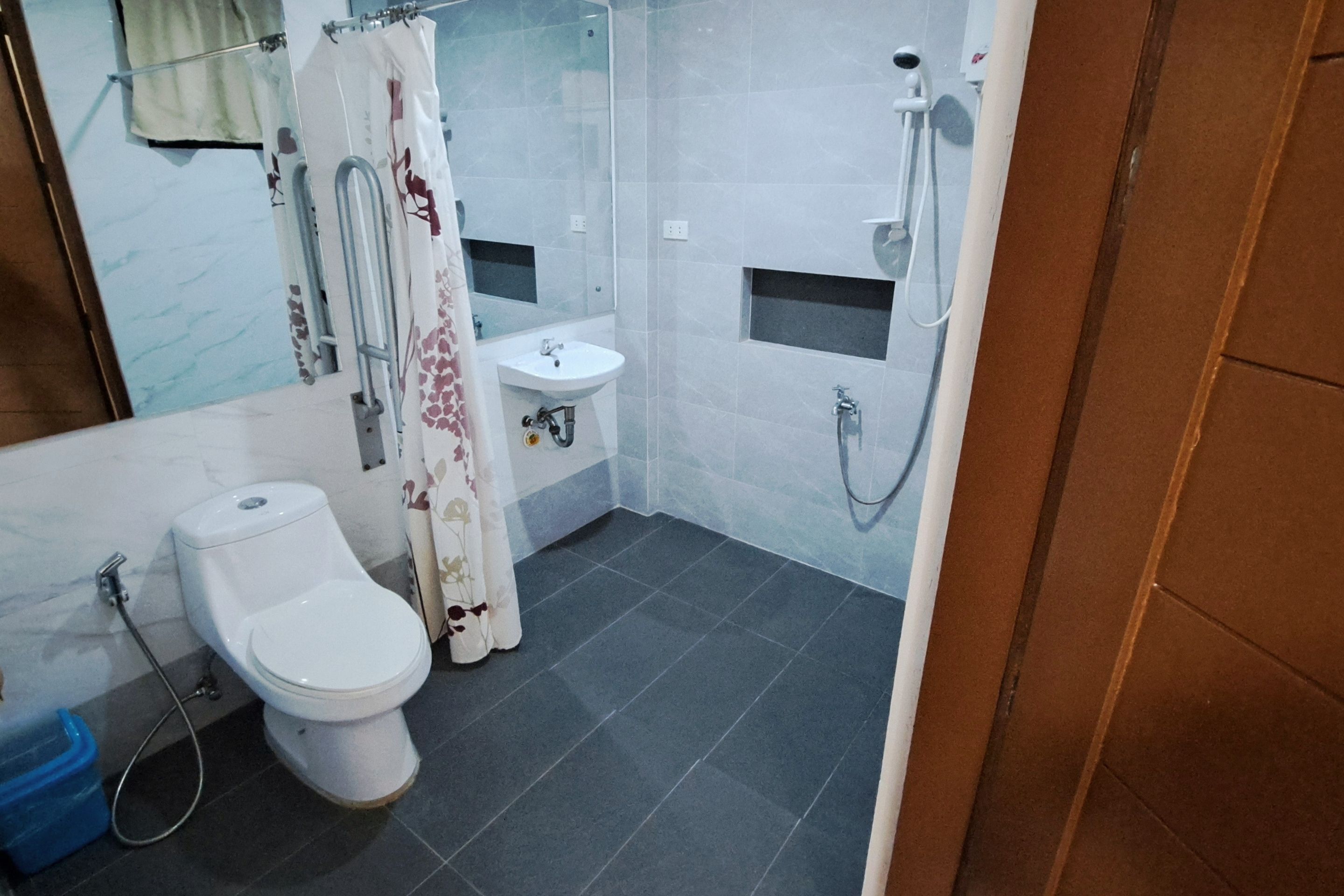 A bathroom with a toilet, sink, shower, and a small window.