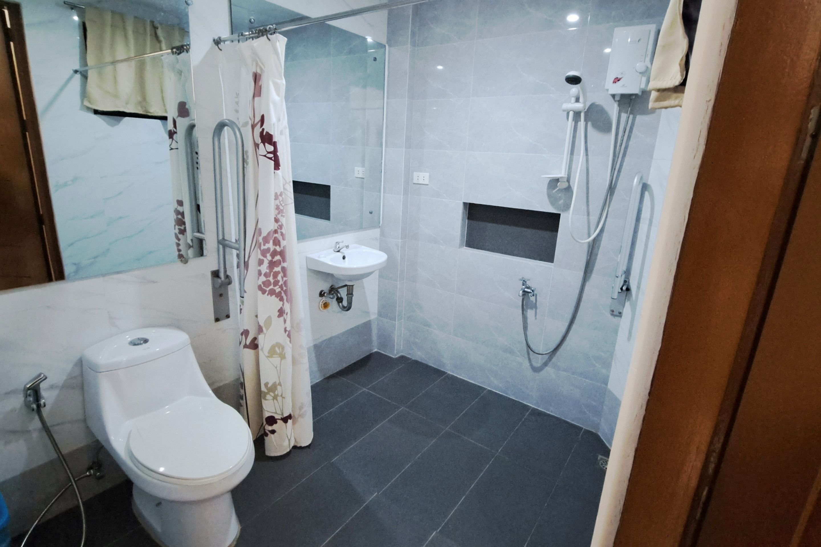 Uma casa de banho moderna com sanita, lavatório, chuveiro e cabine de duche com parede de vidro.