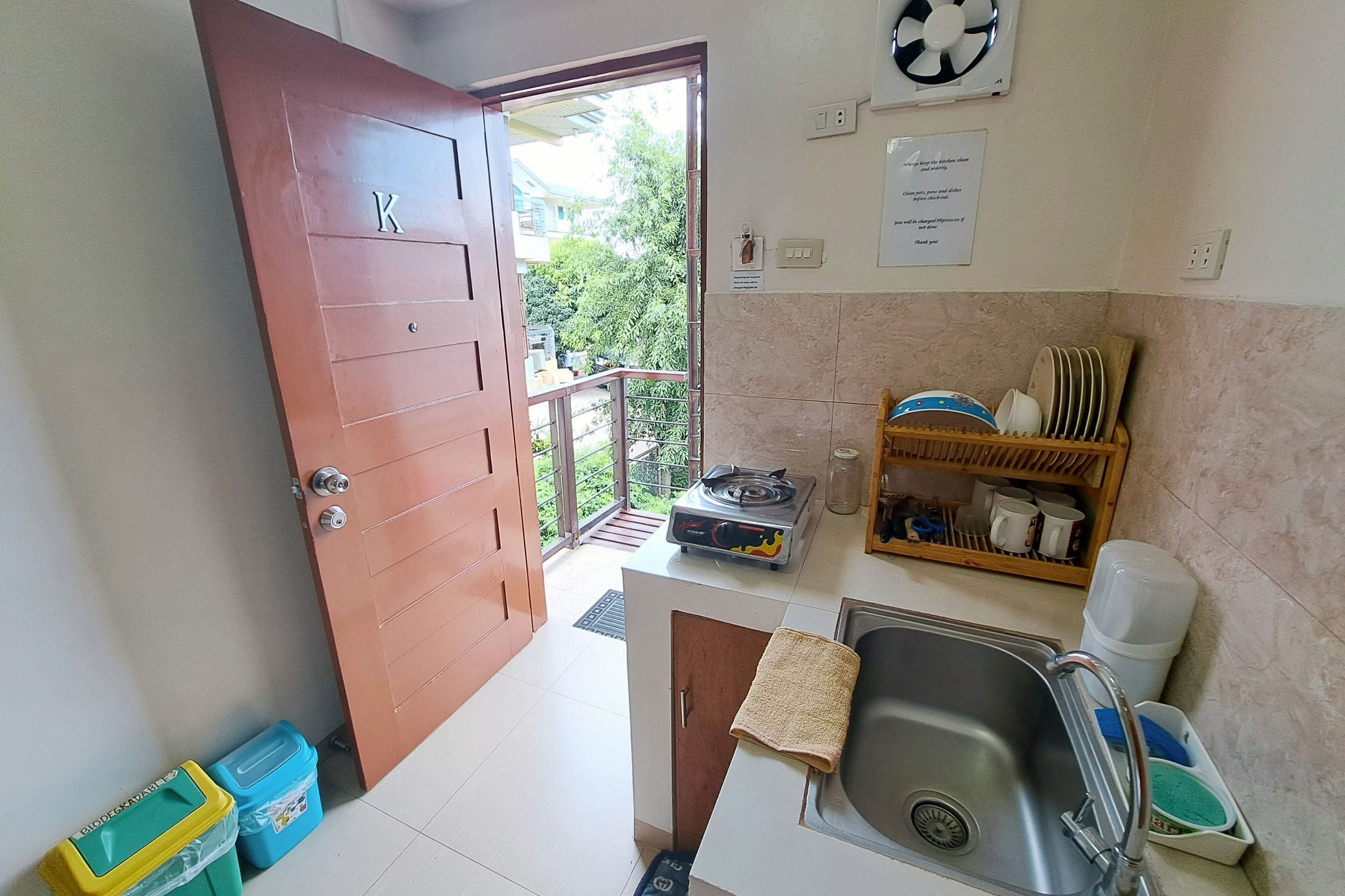 A compact kitchen with a sink, a stove, and a small shelf with dishes.