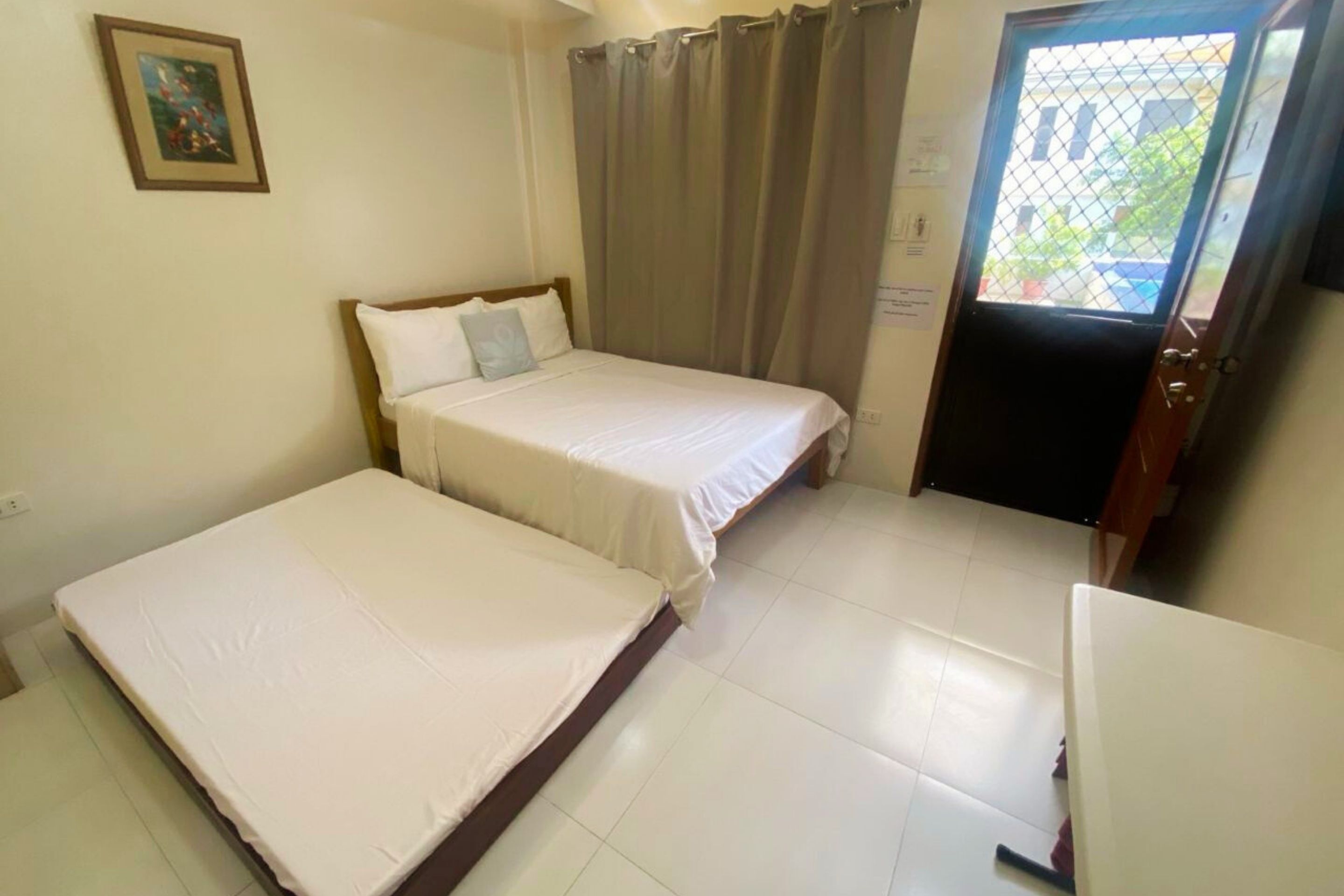 A room with two beds, a door with a window, and a small table.
