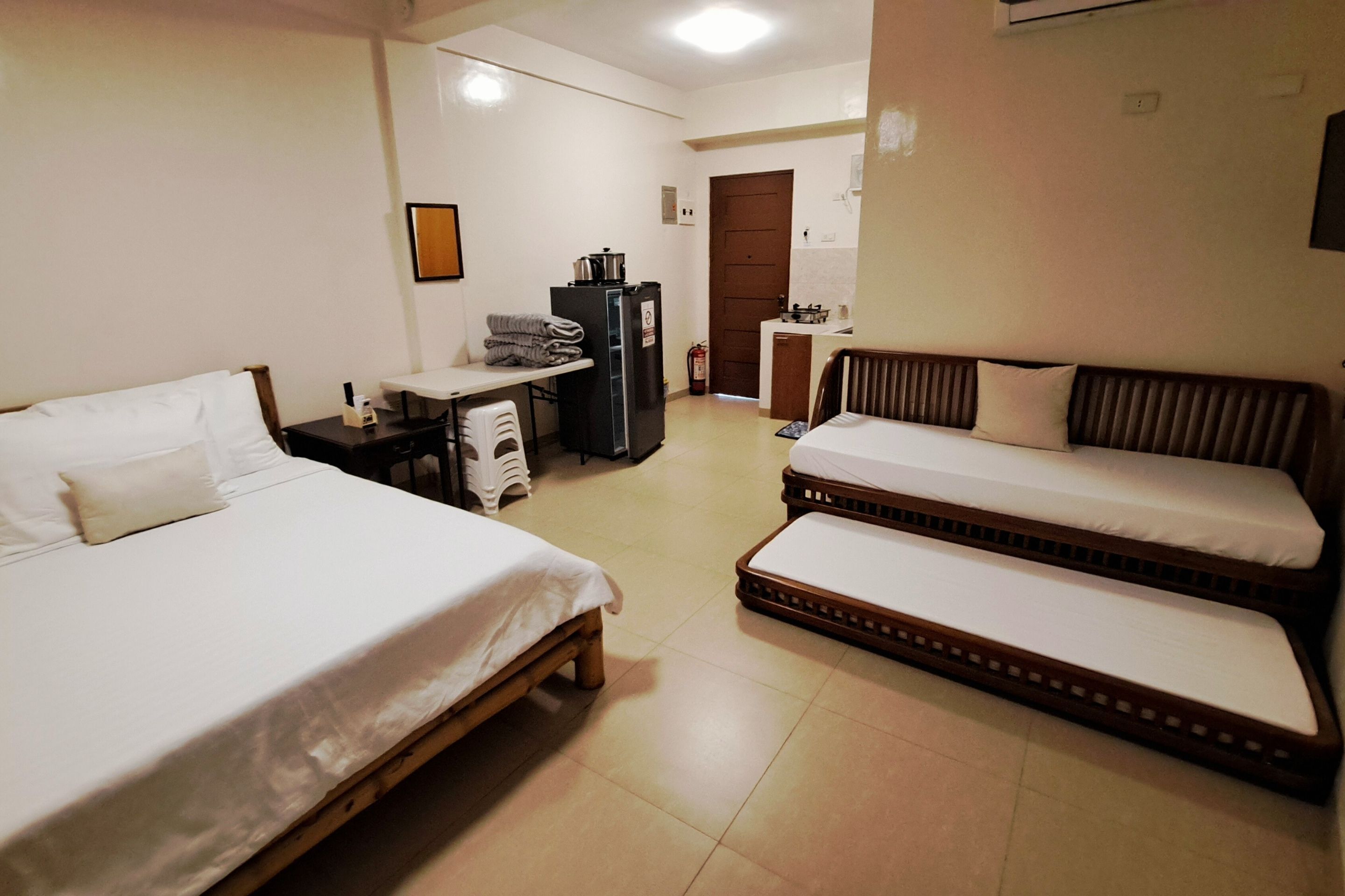 Una habitación de hotel con dos camas individuales, un escritorio pequeño con una silla, un refrigerador y una kitchenette.