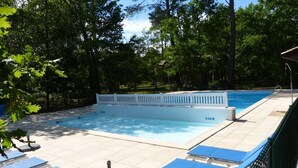 A swimming pool with a white deck, surrounded by trees and a white fence. - Villa Marina de Talaris sur le lac de Lacanau (Lacanau)
