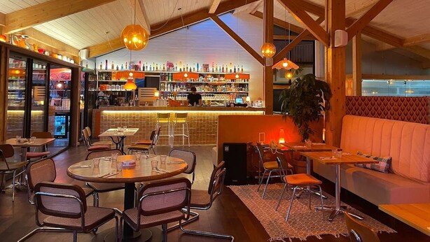A cozy bar area with wooden beams, round tables, and a bar counter. - Villa Marina de Talaris sur le lac de Lacanau (Lacanau)