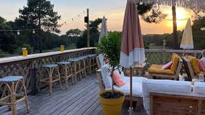 A wooden deck with outdoor seating, including chairs and a table, and a potted plant. - Villa Marina de Talaris sur le lac de Lacanau (Lacanau)