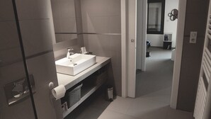 Une salle de bain moderne avec un lavabo blanc, un miroir et des toilettes.