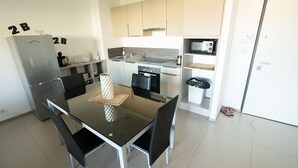 Une cuisine compacte comprenant une table à manger, des chaises, un réfrigérateur, un four à micro-ondes, un four et un évier.