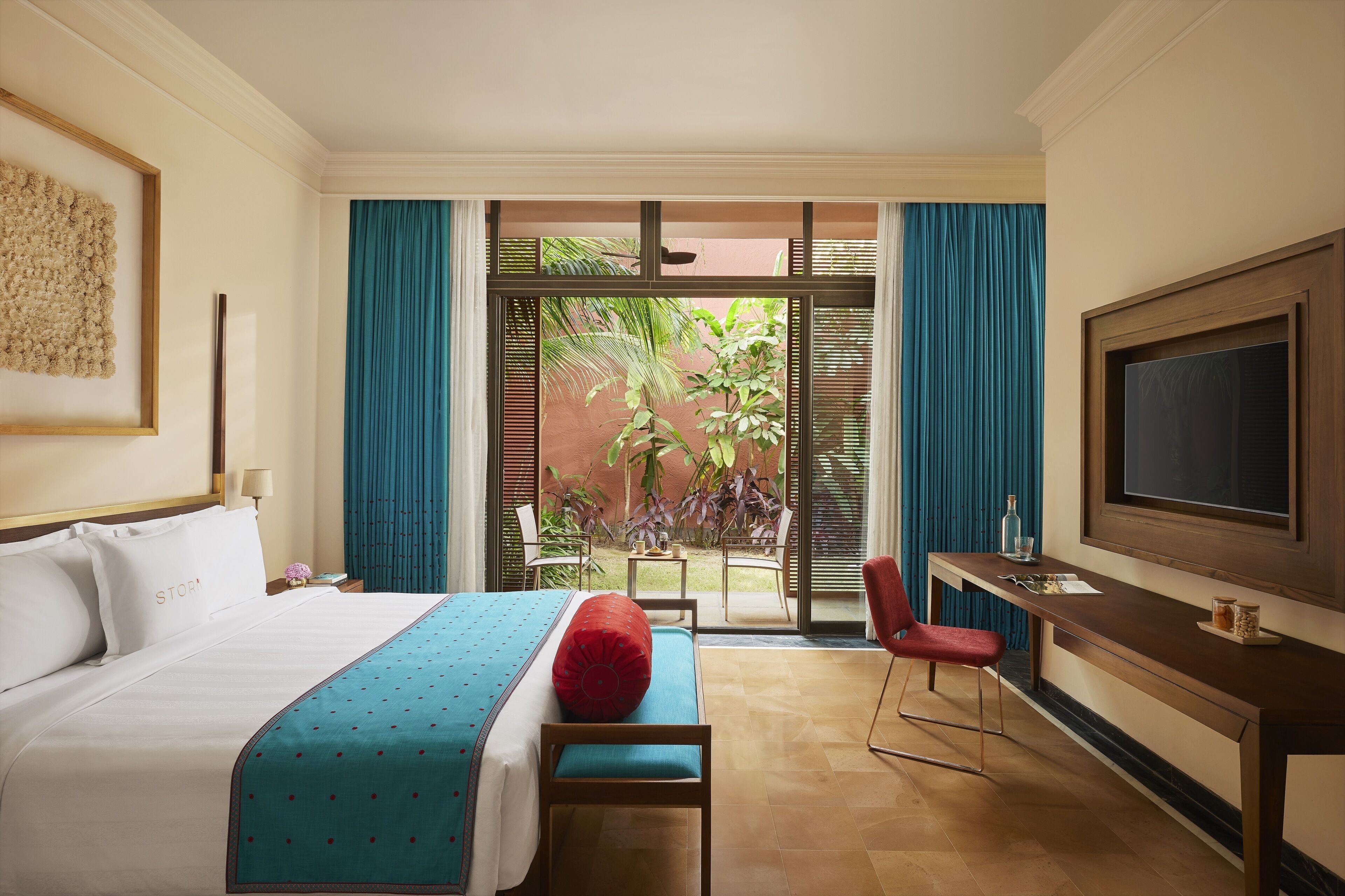 A hotel room with a bed, a desk, a TV, and a view of the outdoors.