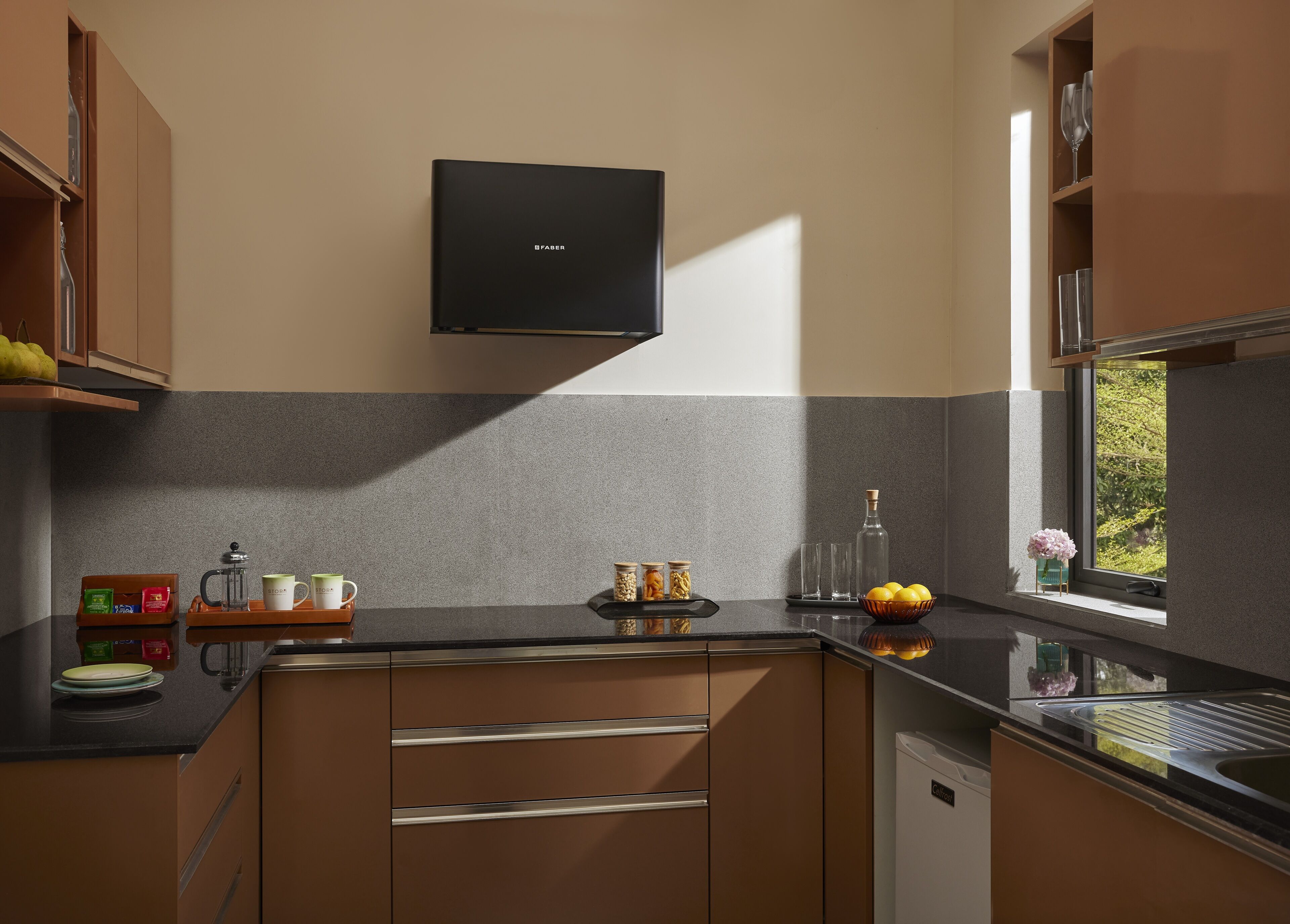 A modern kitchen with a built-in stove, a coffee maker, and a bowl of lemons on the counter.