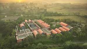 Un moderno resort ecológico con edificios cilíndricos, techos verdes y abundante vegetación circundante.