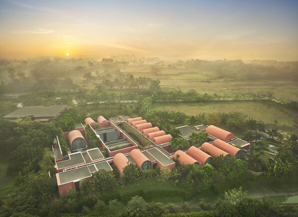 Un moderno resort ecológico con edificios cilíndricos, techos verdes y abundante vegetación circundante.