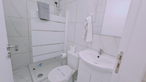 A modern bathroom with a toilet, sink, and shower. - STAY Terra Cota Studio (Limassol)
