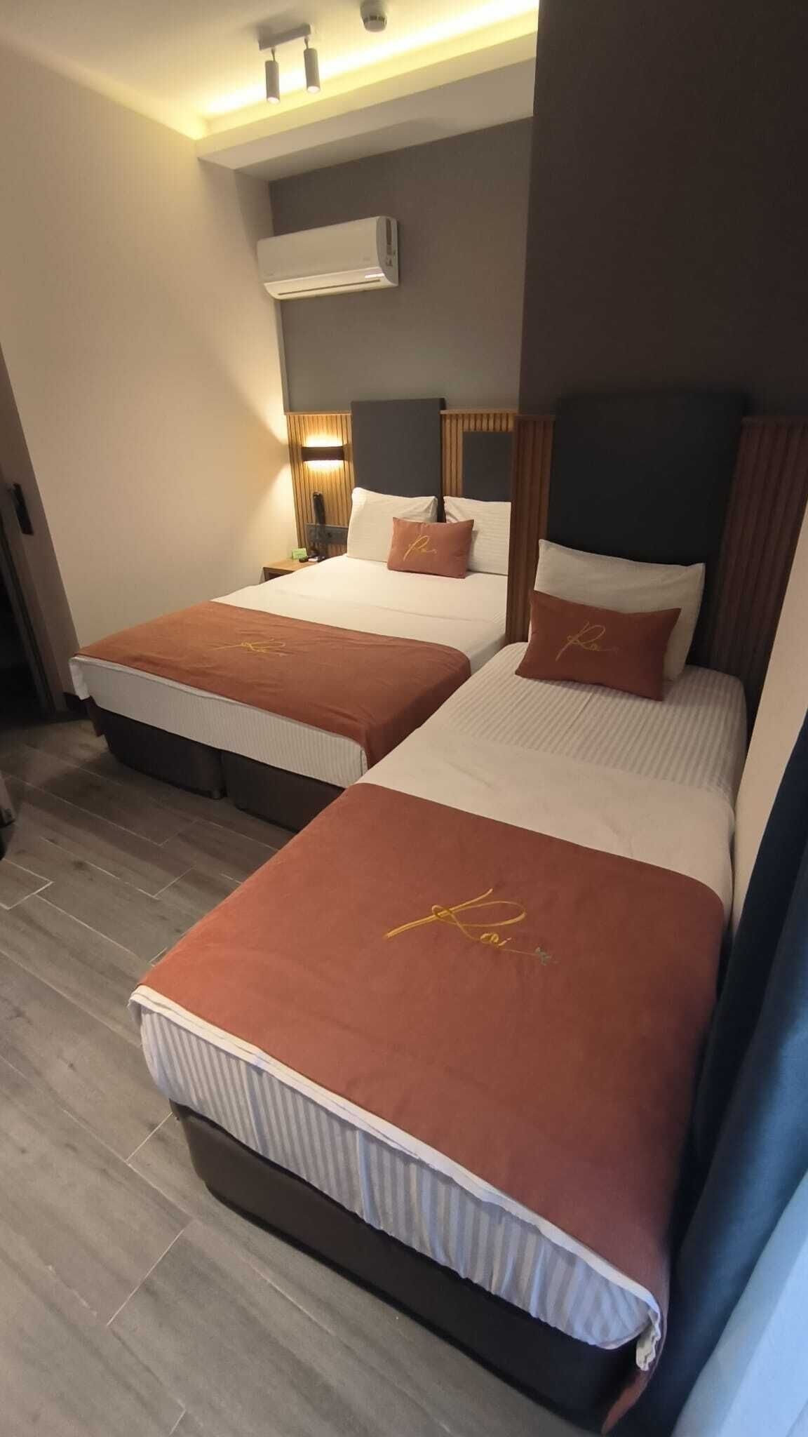 Ett hotellrum med två sängar, en väggmonterad luftkonditioneringsanläggning och en sänglampa.