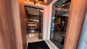 A hotel reception area with a reception desk, a black doormat with 'Koi Hotel' written on it, and a glass door leading inside. - Roi Hotel Izmir (Izmir)