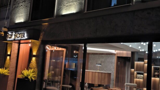 A hotel exterior at night with a modern design, featuring a reception area with seating and a visible interior through large windows. - Roi Hotel Izmir (Izmir)