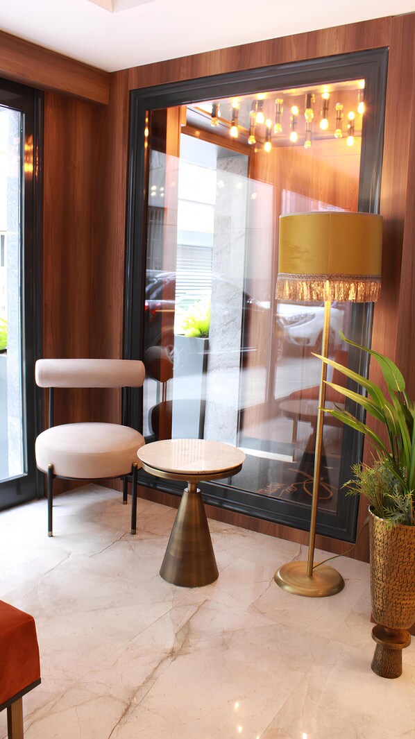 A modern interior with a round table, a cushioned chair, a floor lamp, and a potted plant.