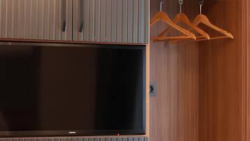 A wardrobe with vertical slats, a flat-screen TV, and wooden hangers.