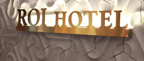 Una pared texturizada con un letrero dorado que dice "ROHOTEL".