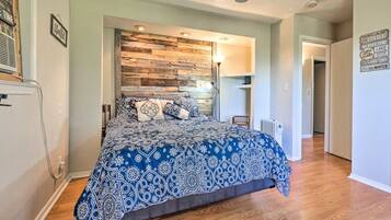A bedroom with a bed, a wooden accent wall, and a hallway leading to another room.