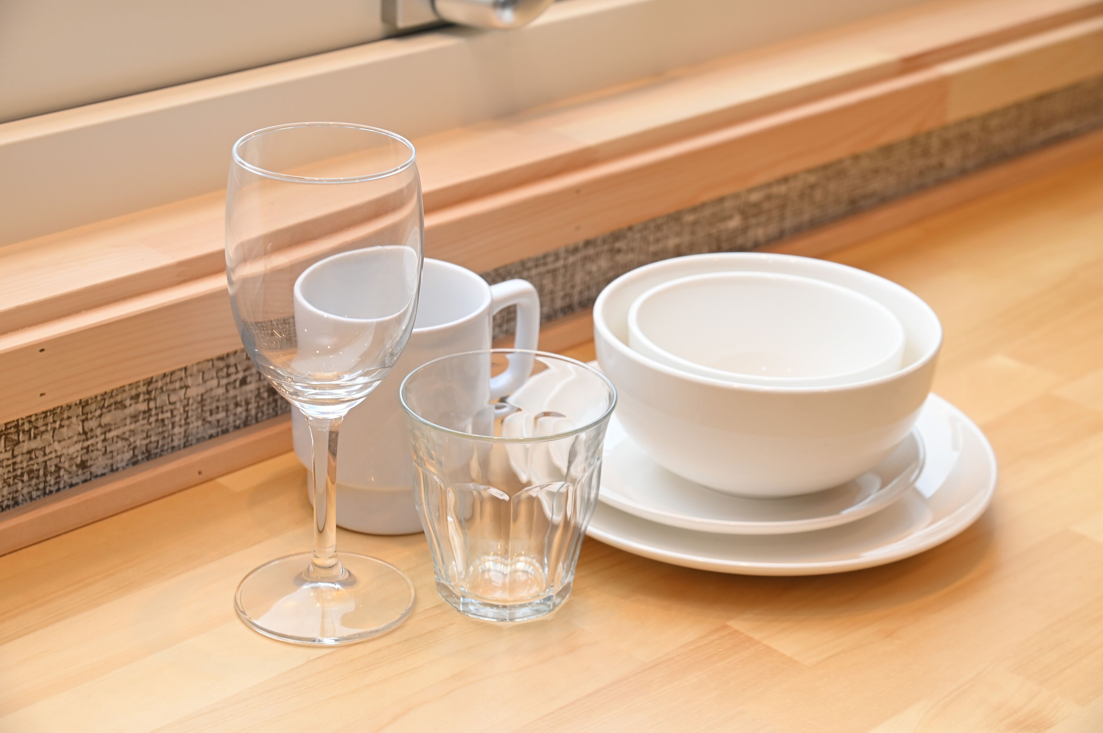 A set of white glassware and plates on a wooden table.