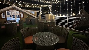 An outdoor seating area with wicker furniture and string lights. - Rajgriha Kasauli (Kasauli)