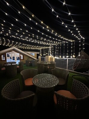 An outdoor seating area with wicker furniture and string lights. - Rajgriha Kasauli (Kasauli)