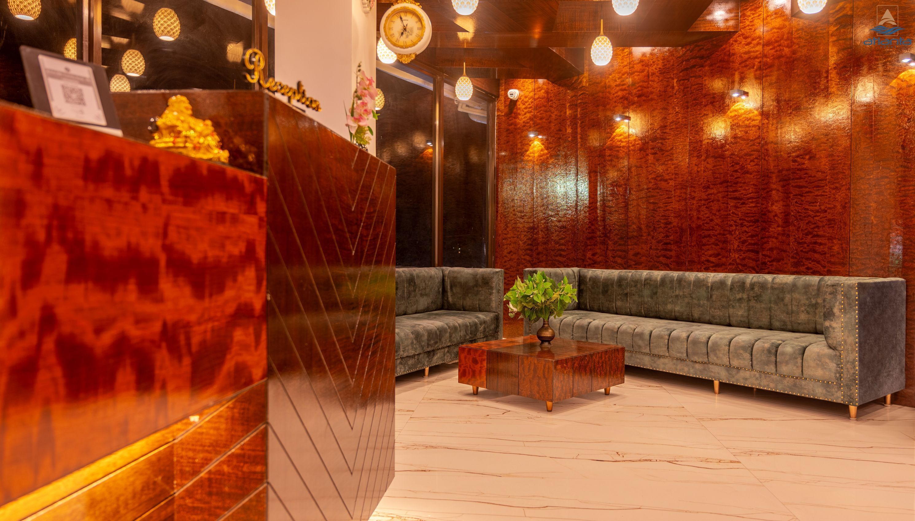 A reception area with a wooden reception desk, a grey sofa, and a coffee table with a plant.