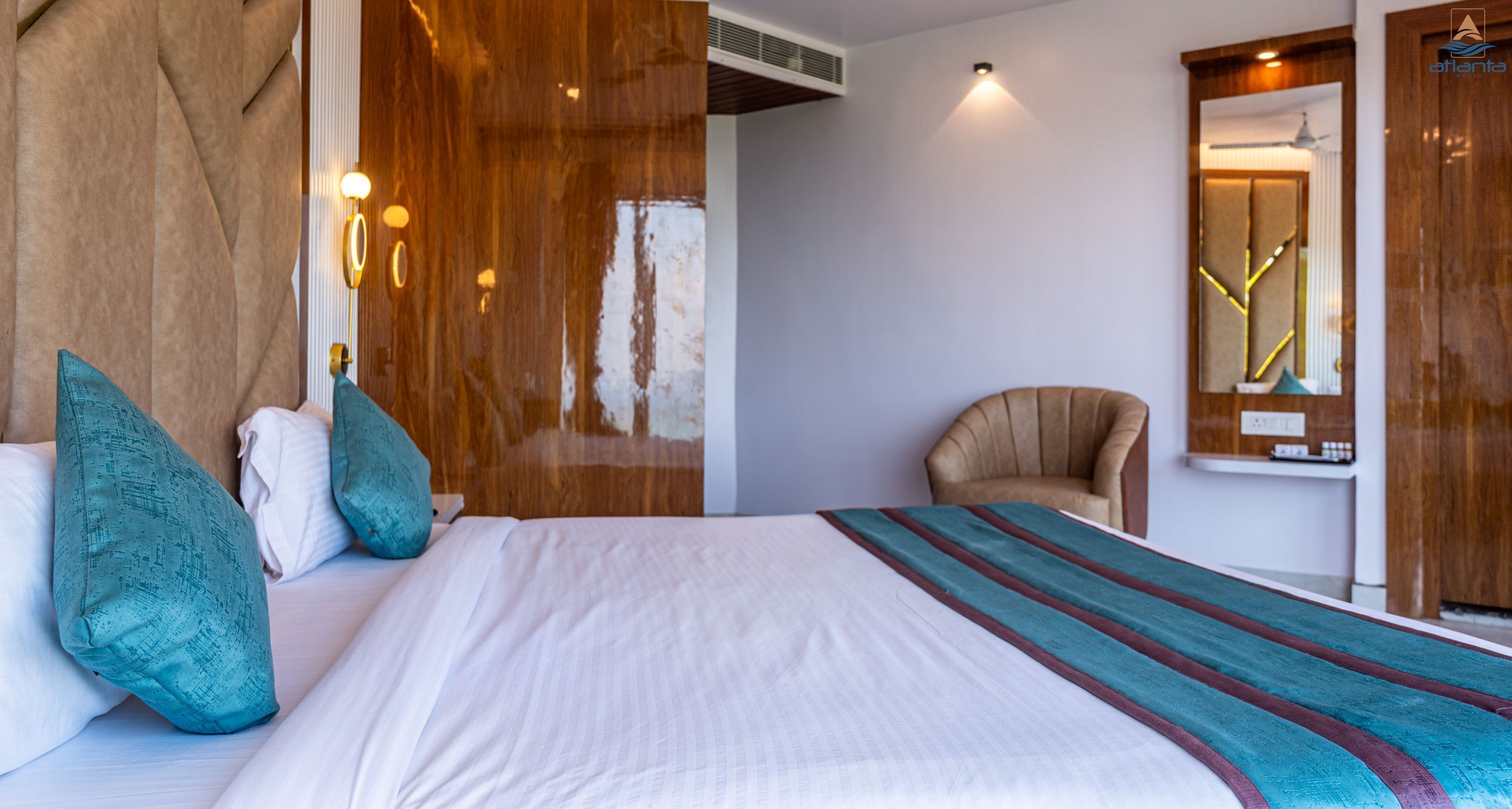A hotel room with a large bed, a chair, a mirror, and a wooden wall.
