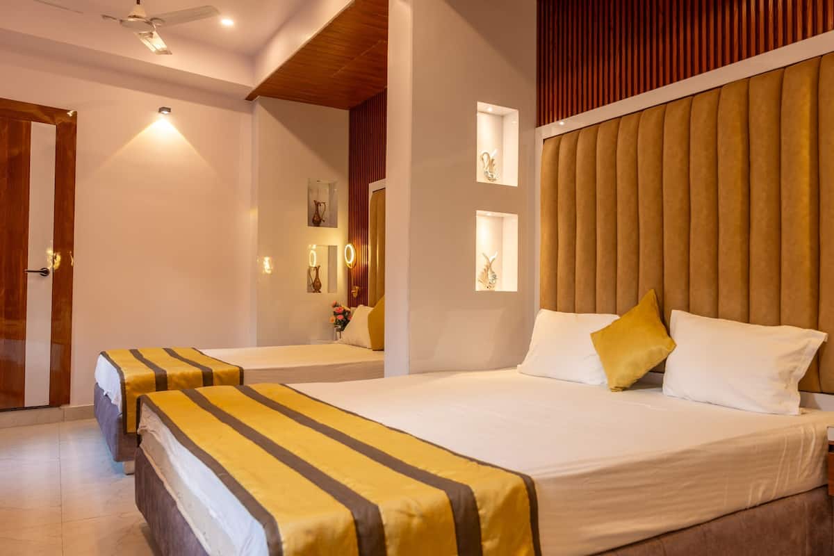 Een hotelkamer met twee bedden, een houten hoofdbord, een nachtkastje met spiegel en een kleine vaas met bloemen.