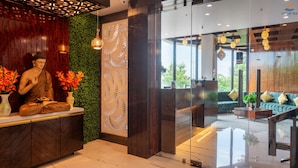 A reception area with a Buddha statue, a green wall, and a modern reception desk.