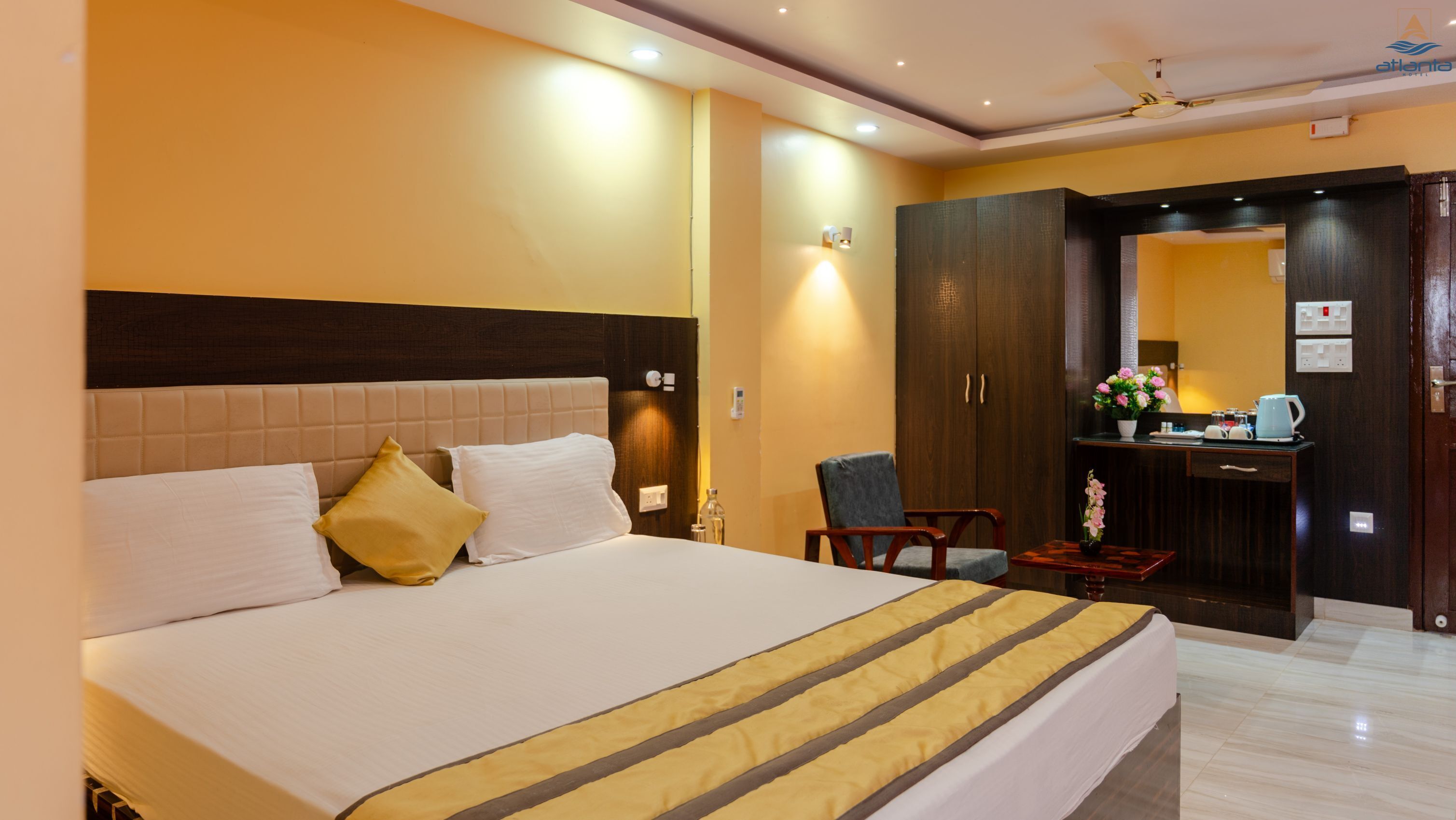 A hotel room with a large bed, a desk, a chair, and a wardrobe.