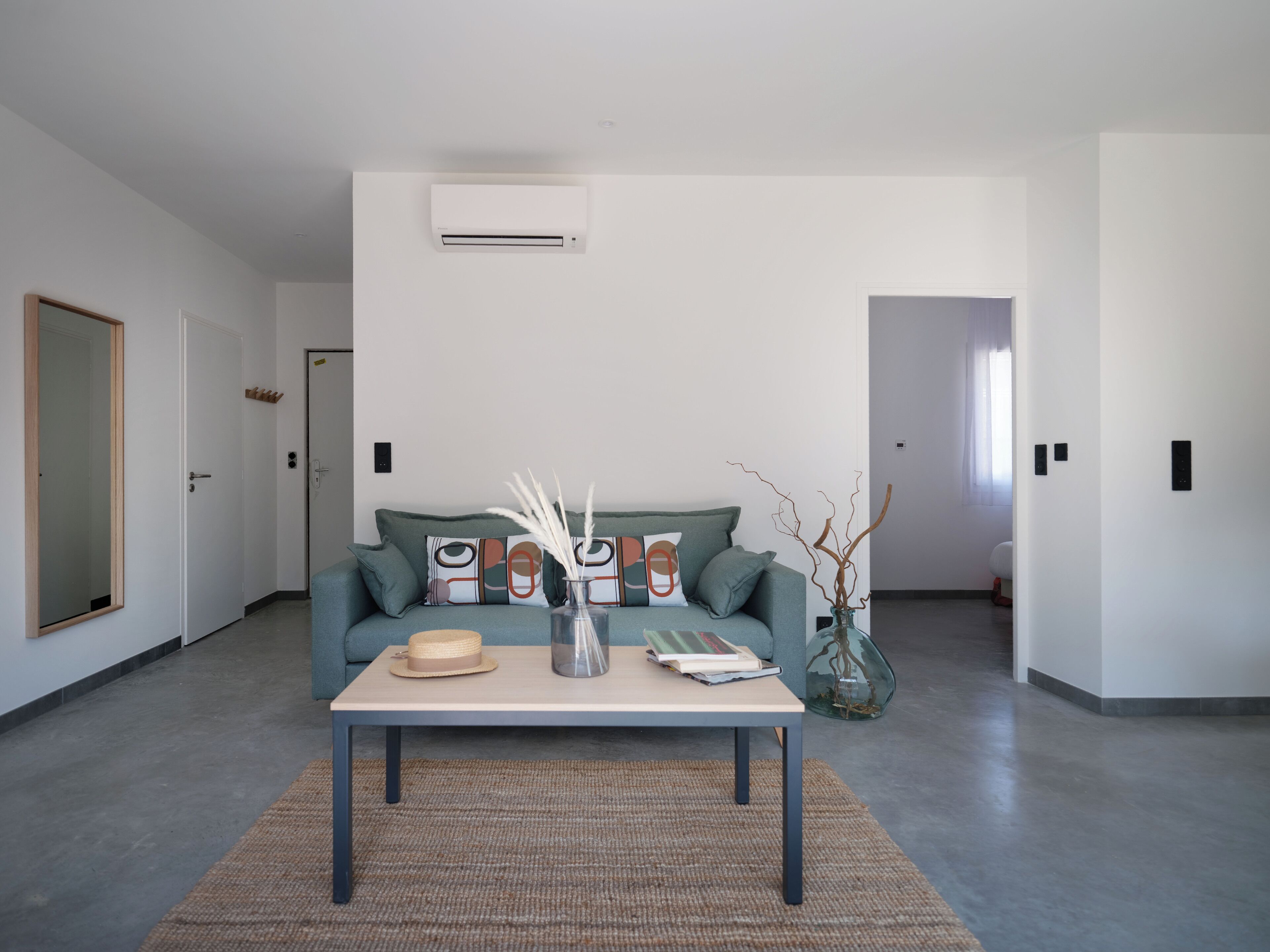 Una sala de estar moderna con un sofá, una mesa de centro y un jarrón con ramas decorativas.