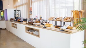 A breakfast buffet with various breads, pastries, and condiments. - Côté Océan (Angoulins)
