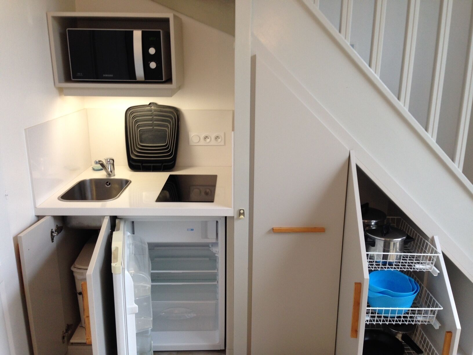 A compact kitchen with a built-in microwave, a sink, and a refrigerator.