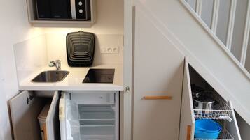 A compact kitchen with a built-in microwave, a sink, and a refrigerator.