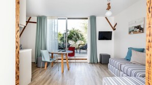 A modern living room with a dining area, a sofa, a TV, and a view of the outdoors. - Côté Océan (Angoulins)