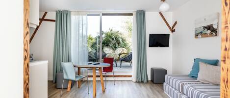 Un salon moderne comprenant un coin repas, un canapé, un téléviseur et une vue sur l’extérieur.