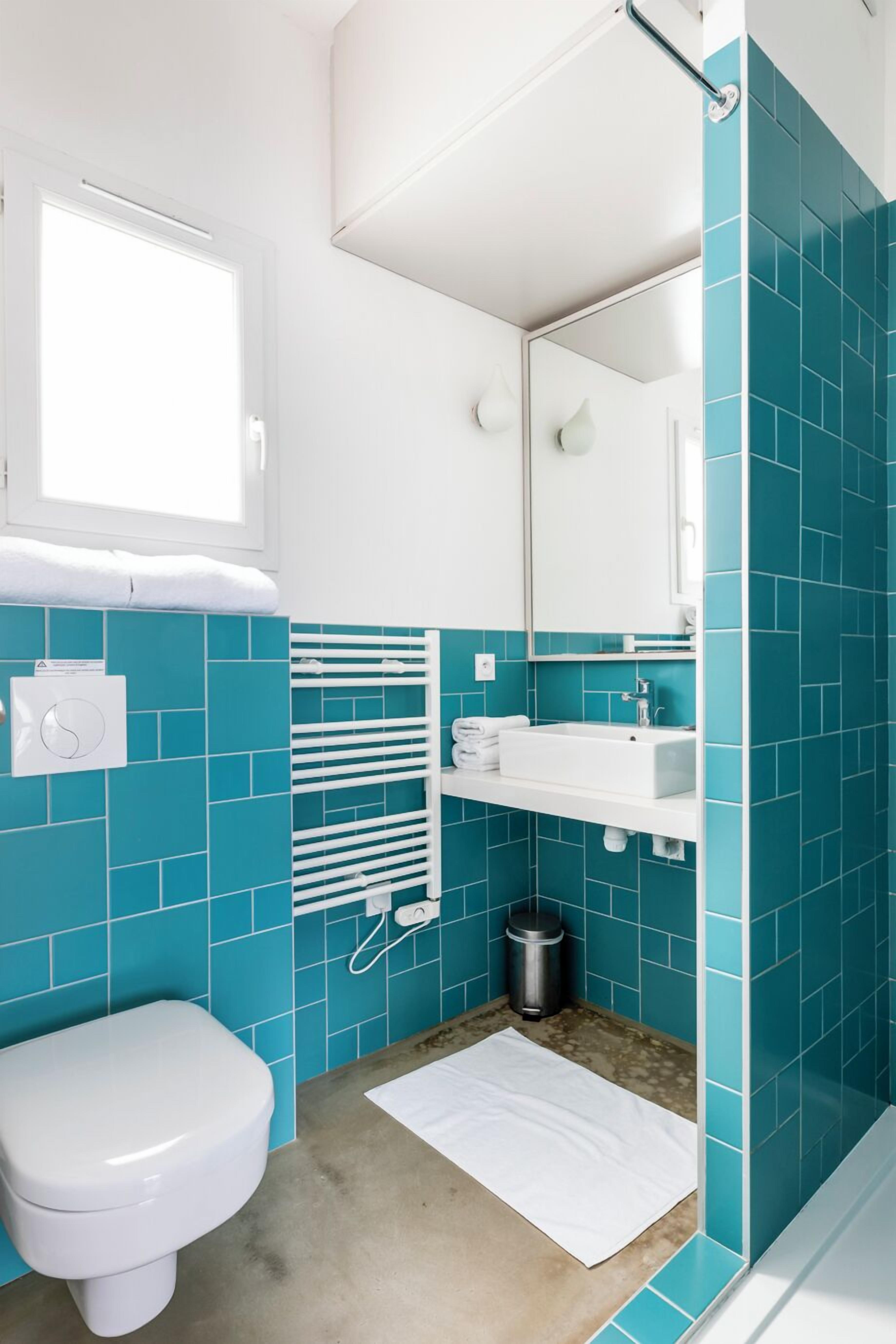A bathroom with a white toilet, a sink with a mirror above it, and a towel rack.