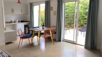 Eine moderne Küche mit Essbereich, großen Schiebeglastüren zu einem Garten und einem kleinen Kühlschrank.