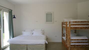 Un dormitorio con cama individual, literas, una ventana con cortinas y un aplique de pared.