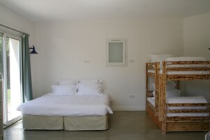 Un dormitorio con cama individual, literas, una ventana con cortinas y un aplique de pared.
