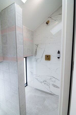 Een douche, vloerverwarming, handdoeken, zeep