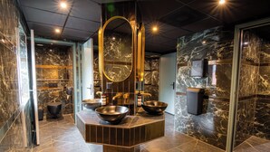 Een moderne badkamer met marmeren wanden, een grote spiegel en twee wastafels.